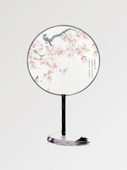 A round Japanese fan with white fabric in a pattern of flowers and birds