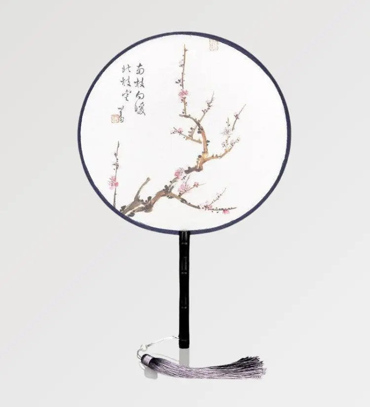 A round fan with Japanese writings decorated with a branch where sakura flowers