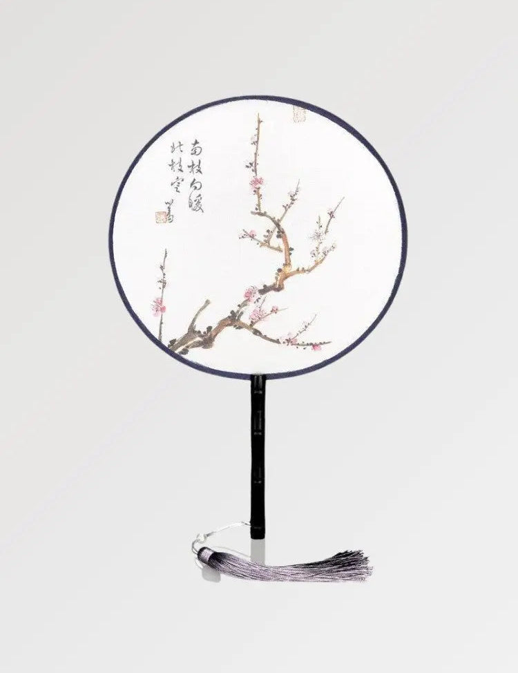 A round fan with Japanese writings decorated with a branch where sakura flowers