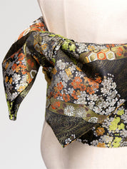 Dark brocade obi belt with orange and white chrysanthemums, green foliage and golden tortoiseshell, close detail of the woven fabric and pattern