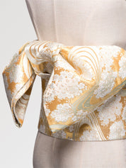Soft gold obi belt woven with white blossom clusters and flowing-water lines, close detail of the woven fabric and pattern