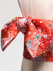Deep red brocade obi belt with white, pink and blue blossoms and gold thread, flat product view showing the full sash and knot