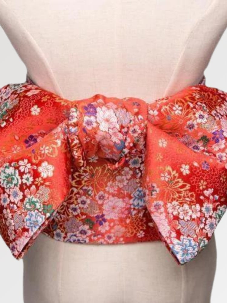 Deep red brocade obi belt with white, pink and blue blossoms and gold thread, close detail of the woven fabric and pattern