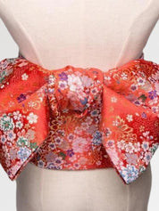 Deep red brocade obi belt with white, pink and blue blossoms and gold thread, close detail of the woven fabric and pattern