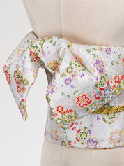 White and silver brocade obi belt with tiny red, green and violet flowers and a gold cord, close detail of the woven fabric and pattern